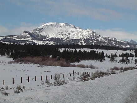 Mammoth Mountain with ski runs toward the top and the city of Mammoth Lakes hidden in the trees on the lower slopes.