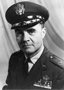 Head and shoulders of man in uniform with peaked cap. He has four rows of ribbons, pilot's wings, and a star on each shoulder.