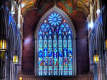 Stained-glass window above the sanctuary of the cathedral depicting the crucifixion, one of three stained-glass windows in the church St. Michael's Cathedral, Toronto.jpg