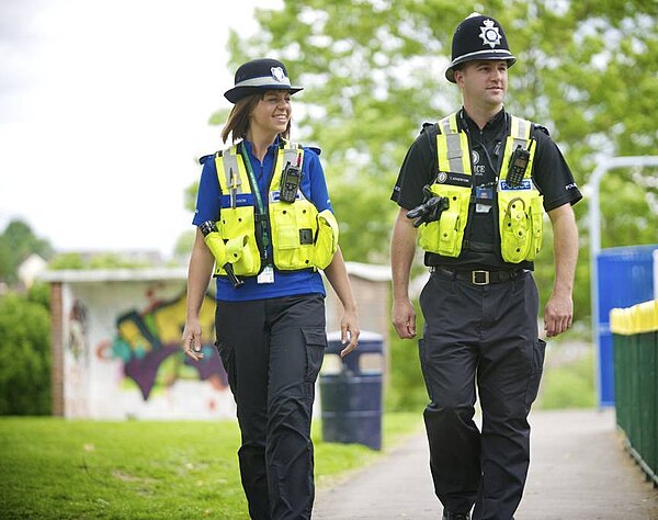 A West Midlands Police PCSO (left) on foot patrol with a constable (right)