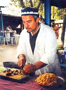 Egy férfi a nemzeti ételt, a plov-ot készíti