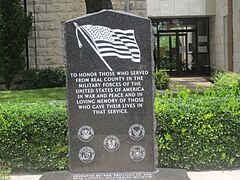 Une plaque de marbre noir gravé du drapeau américain en noir et blanc, suivi d'un texte honorant les militaires américains ayant donné leur vie.