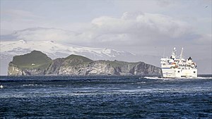 Prom płynie z wyspy Heimaey do Landeyjahöfn na Islandii. Na pierwszym planie wyspa Bjarnarey, w tle wulkan Eyjafjallajökull na Islandii.