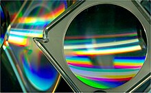 A magnifying glass and CD-ROM discs placed at an angle to the bed show reflection, refraction, and diffraction effects that can be generated. Cds and lens.jpg