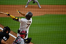 Un joueur de baseball de dos termine son geste de frappe.