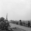 Infantry moving up past a knocked-out German 88mm gun.jpg