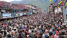 Huge crowd filling a large street with mountains in the background