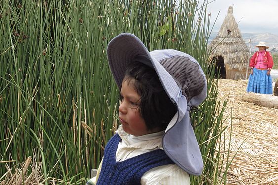 Little boy who lives in one of the floating islands of Uros and his mother in the background