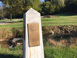 Monument to Ziebold with creek and remains of the mill in background. Monroe City Mill Monument.jpg