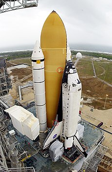 The Space Shuttle stack standing vertically on the launchpad, with a red circle around the bipod foam.
