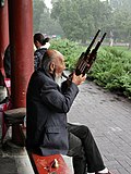 Man playing sheng outdoors, Beijing