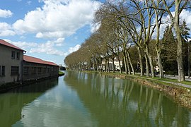 Foto eines von Bäumen gesäumten Kanals rechts von einer Brücke aus.