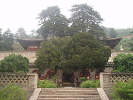 Будівля китайського храму. Збудована на піднятій терасі, а два дерева поруч закривають вид на неї.