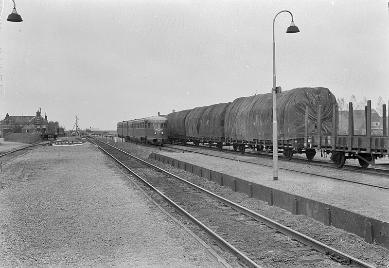 File:HUA-167500-Gezicht op het emplacement van het N.S.-station Baflo te Baflo, met enkele goederenwagens en een naderend diesel-electrisch treinstel DE 2 ("Blauwe Engel", serie 61-106) van de N.S.jpg