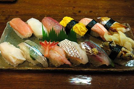 A fancy nigiri assortment.<br>
Top from left: salmon (sāmon), squid (ika), amberjack (hamachi), egg (tamago), crab (kani), octopus (tako)<br>
Bottom from left: boiled spiral shellfish (tsubugai), halfbeak (sayori), sweet shrimp (amaebi), sea bream (tai), sardine (iwashi), oyster (kaki), pickled ginger (gari)