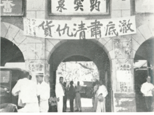 Czarno-biała fotografia sztandaru wisi na bramie Baotu Spring na murach miejskich Jinan.  Po chińsku brzmi „dokładnie posprzątaj wroga”.