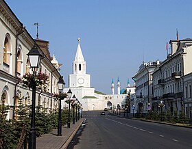 Photographie d'une rue assez étroite avec une tour blanche en fond.