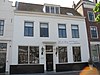 Huis met brede geverfde lijstgevel, plint gepleisterd