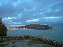 View of Monte Orlando from a former anti-aircraft position on the harbour of Serapo. The Montagna Spaccata is the sharply vertical cliff on the right side of the promontory. The bastions of Charles V can be seen just on the lower left corner of the convent in the wood.