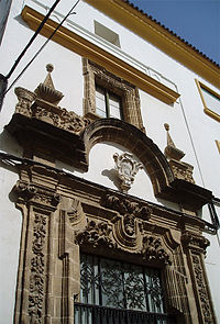 Portada del convento de la calle San Bartolomé, de mediados del siglo XVII. Se aprecia el escudo de la orden, la decoración vegetal y dos figuras humanas (indios que representan la evangelización de los dominicos en América) que portan cestas con frutas y flores.