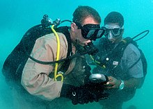 A Navy buddy diver team checking their gauges together US Navy 080710-N-8968M-124 Construction Mechanic 2nd Class Aaron Heldreth checks bottle pressures with his buddy diver, Constable Gaveline Brouet, a Region Security Service diver from St. Lucia.jpg