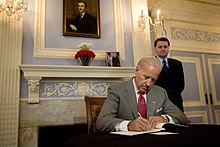 Joe Biden bir masada oturuyor, bir kitap yazıyor