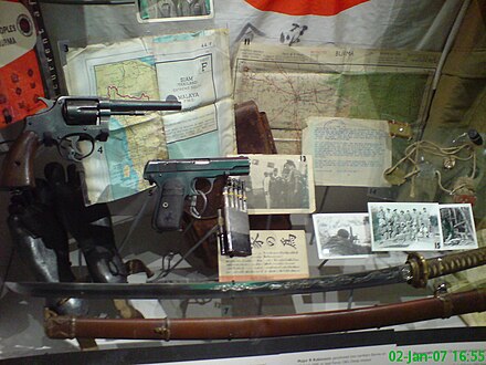 War in the Far East exhibit in the Imperial War Museum London. Among the collection are a Japanese Good Luck Flag, operational map (numbered 11), photographs of Force 136 personnel and guerillas in Burma (15), a katana that was surrendered to a SOE officer in Gwangar, Malaya in September 1945 (7), and rubber soles designed by SOE to be worn under agents' boots to disguise footprints when landing on beaches (bottom left).