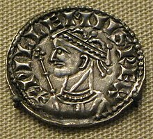 Imagem de moeda de uma cabeça masculina coroada com um cetro ao fundo