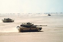 Abrams tanks move out on a mission during Operation Desert Storm in 1991. A Bradley IFV and a logistics convoy can be seen in the background. Abrams in formation.jpg