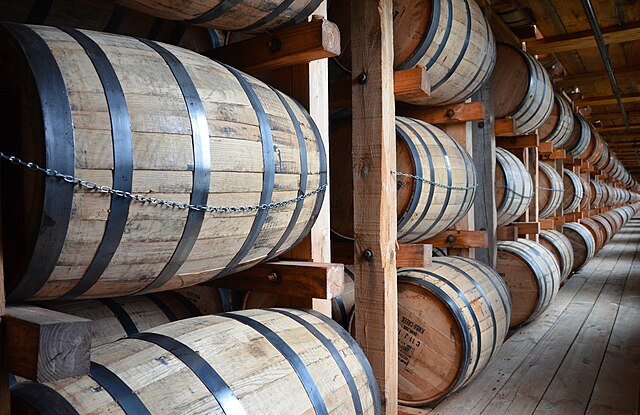 American white oak barrels filled with new bourbon whiskey rest in a rickhouse, giving bourbon its well-known copper color