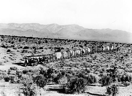 Two Holt 45 gasoline crawler tractors teamed up to pull a long wagon train in the Mojave Desert during construction of the Los Angeles Aqueduct in 1909.