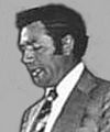 Black and white photo of a man wearing a suit, with his mouth opened