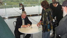 Frans de Waal signing one of his books at the University of Auckland's Owen G. Glenn Building before delivering the third and final lecture in his "Our Inner Ape" series, for the Douglas Robb Memorial Lectures. The book cover visible is Primates and Philosophers: How Morality Evolved. Frans de Waal signing books at the University of Auckland.jpg
