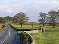 Der Eingang zu Halton Castle markiert den Standort des Nordtores des römischen Kastells. Links die B6318 die direkt über den Hadrianswall verläuft. Im Hintergrund die Hügel des Down Hill.