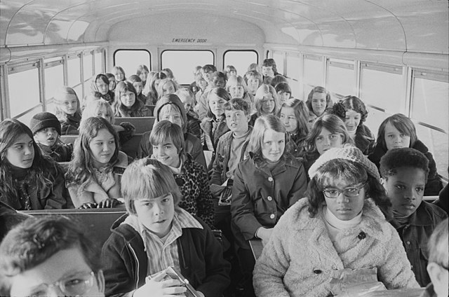 Verschiedene Schulkinder sitzen in einem Schulbus.
