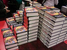 Plusieurs piles d'un même livre à la couverture noire, rouge et jaune, sur lequel est écrit « Harry Potter ».