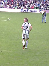 Vista posterior de un hombre blanco rubio vistiendo equipo deportivo en un campo