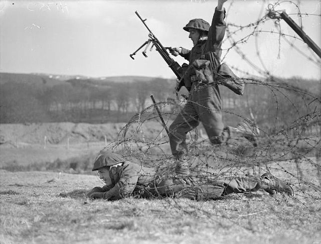 Commandos demonstrate a technique for crossing barbed wire during training in Scotland, 28 February 1942.