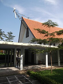 Photographie couleur d'une petite église précédée d'un avent en béton