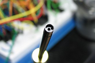 The two holes at the end of a manual wire wrap tool. The wire goes in the one near the edge, and the post is inserted into the hole in the center Wire wrap tool.jpg