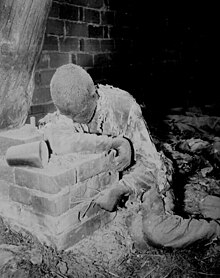 A photograph originally captioned "This victim of Nazi inhumanity still rests in the position in which he died, attempting to rise and escape his horrible death. He was one of 1016 prisoners savagely burned to death by Nazi SS troops. Gardelegen, Germany; 16 April 1945" Buchenwald burned alive ww2-179.jpg