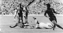 photo en noir et blanc montrant des footballeurs sur un terrain dont deux à terre après un tacle