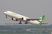 Aircraft in flight. Side view of twin-engine jet with extended landing gear and flaps.