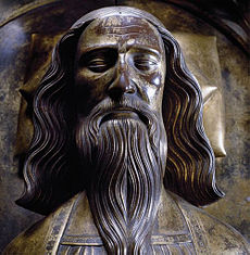 Bronze effigy of man's face with flowing shoulder-length hair and long moustache and beard