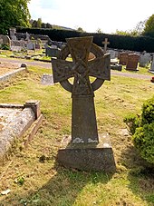 The headstone is made of stone and is in the form of a celtic cross