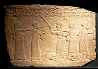 Humiliation of the Elamite King, forced to serve food at the court of Ashurbanipal. Inscription "...the kings of Elam, whom with the aid of Ashur and Ninlil my hands captured . . . they stood(?), and their own hands prepared their royal meal, and they brought it in before me".[9]