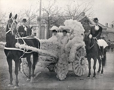 Ima Hogg and an unidentified woman are seated in a horse-drawn carriage, decorated with flowers for the Tekram Parade, part of Houston's No-Tsu-Oh festival. Late 1890s