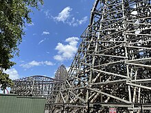 Una vista de las diversas estructuras de soporte y vías de Iron Gwazi desde un sendero en 2022