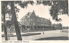 Photograph of a photo postcard from 1910, which shows a block (magazine building) of the Corps Clothing Office from (later so named) Langemarckplatz (viewing direction: west).  Caption under the postcard: “Koblenz a.  Rh. Langemarck barracks. "