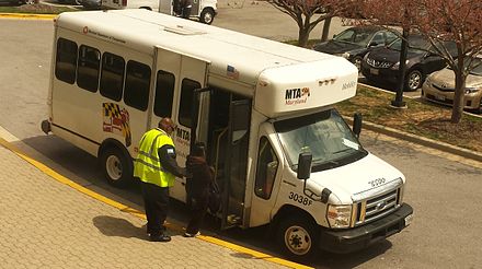 MTA Mobility vehicle operator assisting a customer in boarding a paratransit vehicle